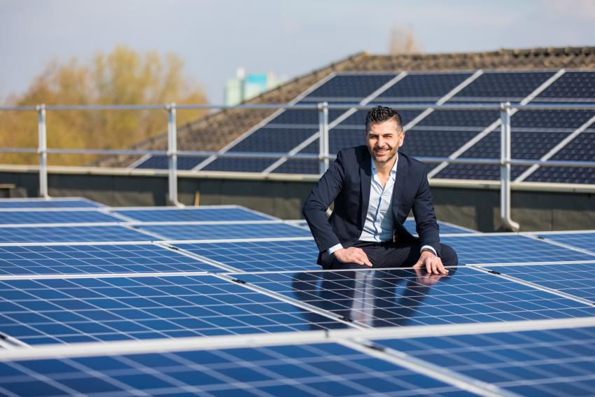 Collega geknield tussen zonnenpanelen op een dak