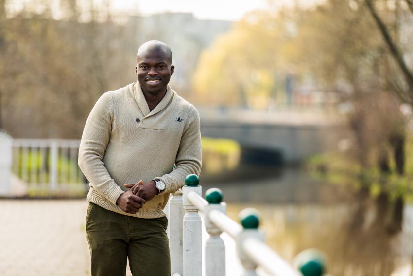 Foto van een collega leunend tegen een hek bij het water